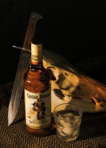 A Captain Morgan bottle with ice glass and animal skull in dramatic lighting.